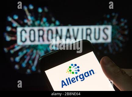 China. 20th Mar, 2020. In this photo illustration the Irish-domiciled pharmaceutical company Allergan logo seen displayed on a smartphone with a computer model of the COVID-19 coronavirus on the background. Credit: Budrul Chukrut/SOPA Images/ZUMA Wire/Alamy Live News Stock Photo