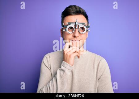Young handsome caucasian man wearing optometrical glasses over purple background with hand on chin thinking about question, pensive expression. Smilin Stock Photo