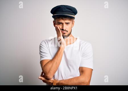 Young driver man with beard wearing hat standing over isolated white background thinking looking tired and bored with depression problems with crossed Stock Photo