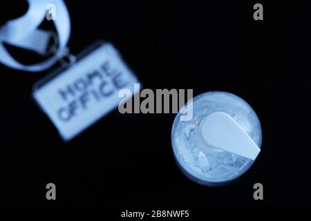 A white clear plastic bottle with transparent hand sanitizer gel with a badge for homeoffice on a black background. Concept for coronavirus covid-19, Stock Photo