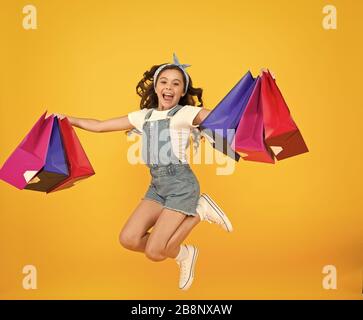 Real happiness. happy small girl after successful shopping. energetic child jump with heavy bags. holiday gifts in packages. cyber monday. hurry up its total sale. Kids fashion. Sales and discounts. Stock Photo