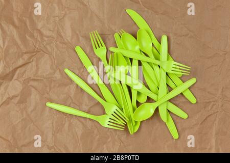 Biodegradable reusable recyclable green forks, spoons, knifes made from corn starch on brown crumpled craft paper. Eco, zero waste, alternative to pla Stock Photo