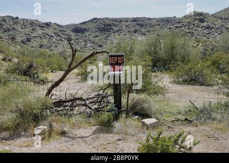 A keep out private property sign on a fence outside a lot of land in the Arizona desert. Stock Photo