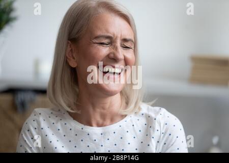 Happy middle aged blonde woman laughing at funny joke. Stock Photo