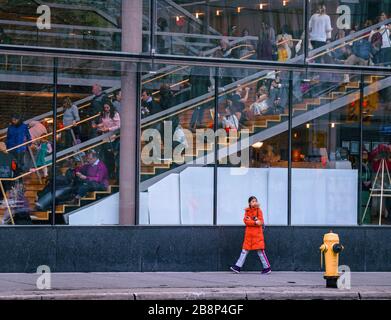 TORONTO, CANADA - 01 04 2020: A girl walking along the University avenue in front of glass wall of the Four Seasons Centre for the Performing Arts Stock Photo