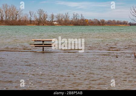 Detroit, Michigan, USA. 22nd Mar, 2020. Record high water levels on the Great Lakes have led to shoreline erosion and flooding. A picnic table on Belle Isle, a state park in the Detroit River, is far from dry land. Credit: Jim West/Alamy Live News Stock Photo