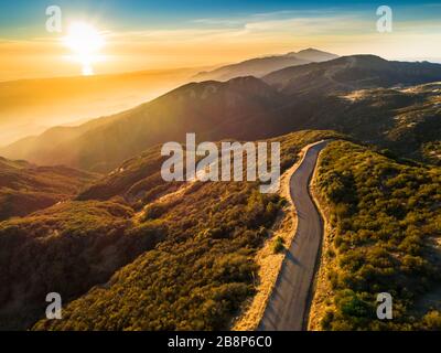 Aerial view of a winding road along the edge of a lake surrounded by ...