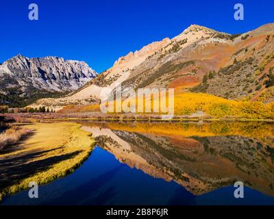 Aerial view of North Lake with reflections of fall aspen and mountains .