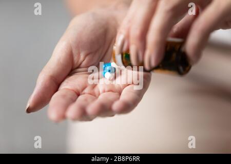Close up older female hands taking pills out of bottle. Stock Photo