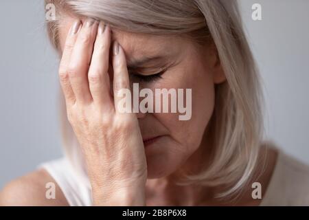 Unhealthy middle aged sad woman touching forehead. Stock Photo