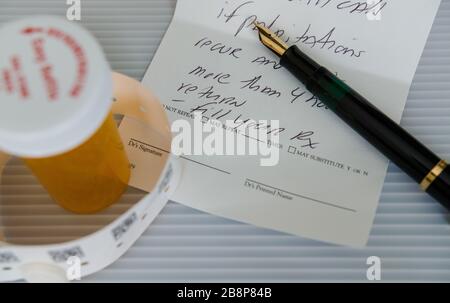 A fountain pen on a prescription for heart problems. Next to it, a medicine container and a hospital bracelet. Stock Photo