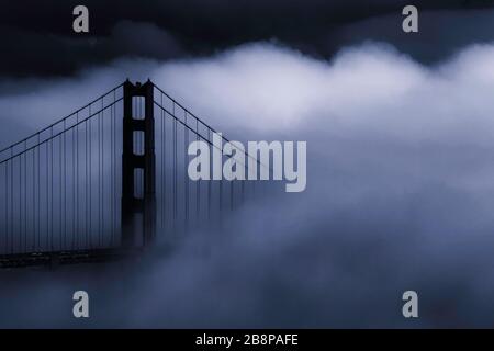 Golden Gate Bridge partially obscured by fog at dusk, San Francisco, California, United States, North America, blue monochrome