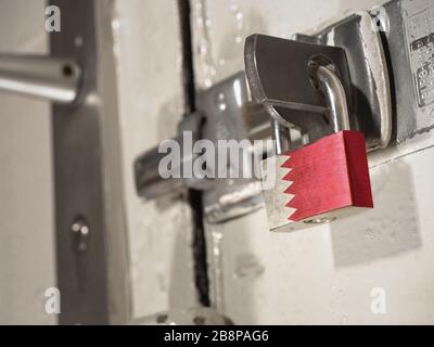 A bolted door secured by a padlock with the national flag of Bahrain on it.(series) Stock Photo