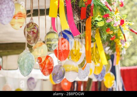 Hanging Easter Eggs with colorful stripes from the top of the wooden roof. Concept of religious holiday decoration in spring, Stock Photo
