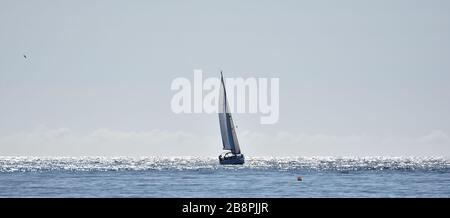 Sailing boat in a Mediterranean sea shining by the rays of the morning sun Stock Photo