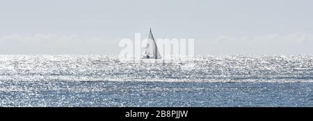 Sailing boat in a Mediterranean sea shining by the rays of the morning sun Stock Photo