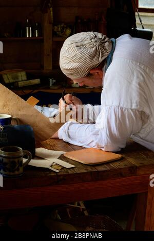 Colonial Williamsburg leather worker using 18th century tools. Stock Photo