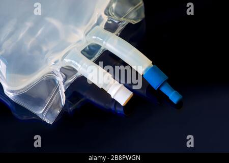 IV bag with medication ports and IV tubing on dark blue. Stock Photo