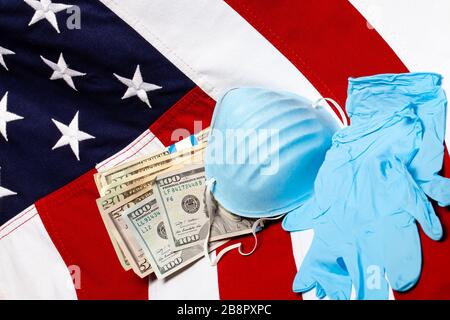 Respiratory mask with cash money and gloves in front of the american flag, angled Stock Photo