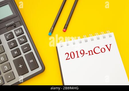 Epidemic concept, coronavirus as a pandemic. Notepad with two pencils and a calculator on a yellow background Stock Photo