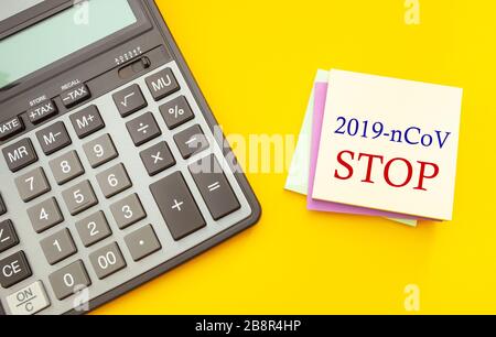 Stop epidemic concept, coronavirus pandemic. Modern calculator with stickers for notes on a yellow background, top view Stock Photo