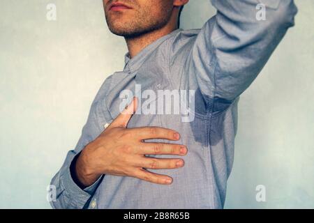 Young man with sweating under armpit. wet spot on my blue shirt from sweat. Stock Photo