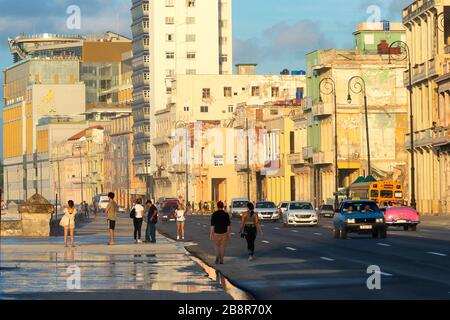 Tourists and locals walking in the Malecon Promenade, in Havana, Cuba. Road and pedestrian traffic visible in front of colonial style buildings. Stock Photo