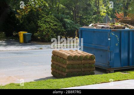 Installation of a modern landscape stacks of sod rolls for new lawn and dumpster full garbage container residential building construction home Stock Photo