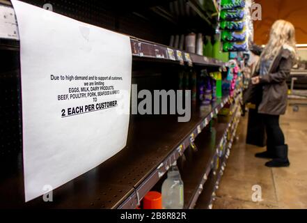 Coronavirus related sign rationing food at a supermarket with shopper in the distance Stock Photo