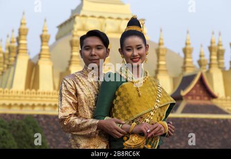 Beautiful Happy Young Couple, A Man and Woman dressed in Traditional Ethnic Laos Clothing at Pha That Luang, or Great Stupa in Vientiane City Center Stock Photo