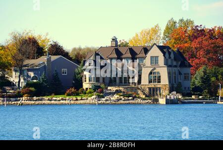 Alexandria Bay, New York, U.S.A - October 24, 2019 - The view of waterfront homes surrounded by striking fall foliage along St Lawrence River Stock Photo