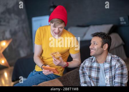 Young man in a red hat showing something on internet to his friend Stock Photo