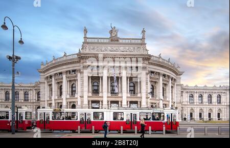 Vienna, Austria. Famous Wiener Ringstrasse with historic Burgtheater (Imperial Court Theatre) and traditional red electric tram at sunrise Stock Photo