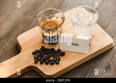 Fresh brewed black Espresso coffee and water in shot glasses served on wooden platter ready to drink Stock Photo