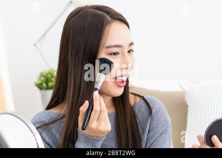 Young beautiful Asian woman professional beauty vlogger doing cosmetic makeup tutorial at home Stock Photo