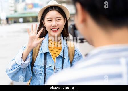 Smiling beautiful Asian woman tourist travel vlogger say hi to camera in the city Stock Photo