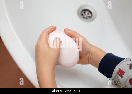 boy washes hands with soap in bathroom. Personal hygiene practices. Stock Photo