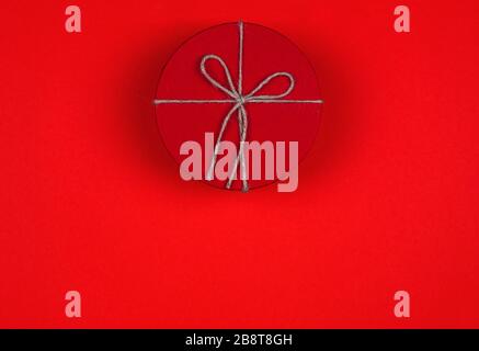 Closed red round gift box on red background. Top view. Gift for the holidays of New Year, Christmas, Valentine's day, birthday Stock Photo