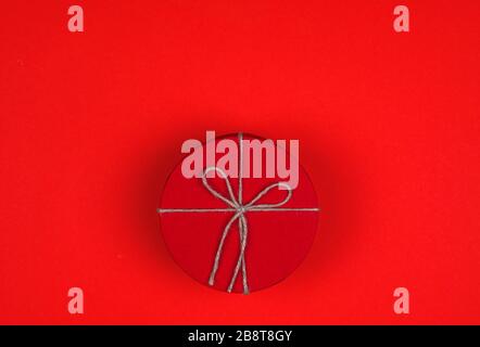Closed red round gift box on red background. Top view. Gift for the holidays of New Year, Christmas, Valentine's day. Stock Photo