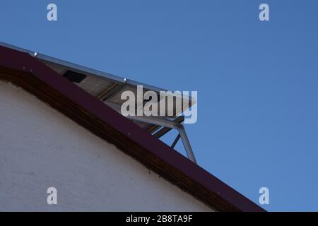 solar panel underside installation on roof top with a clear blue sky background, photovoltaic panel viewed from below on roof Stock Photo