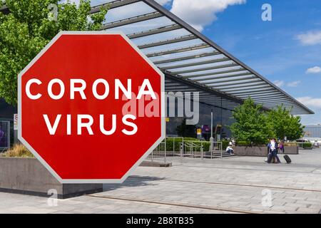 Concept image with large red Coronavirus warning sign in front of Heathrow terminal, concept for travel restrictions Stock Photo
