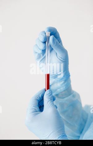 Close up of doctor hand holding blood sample. Medical equipment. Blood test. A doctor wearing personal protective equipment including mask, goggle, an Stock Photo