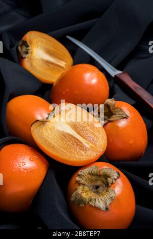 Fresh ripe persimmon fruit, winter fruit, cut on board and black background