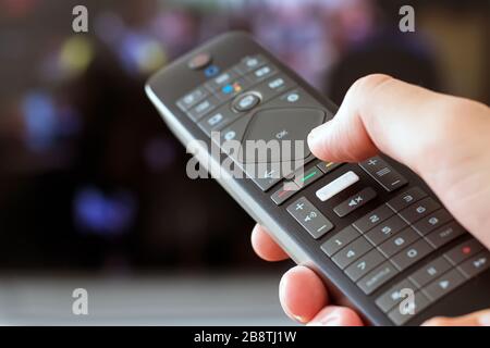 Hand holding a remote control close-up tunring on TV Stock Photo