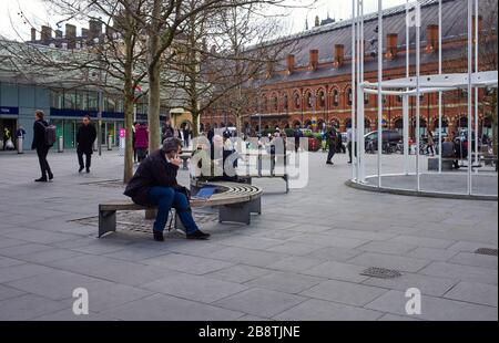 People sitting outside of Kings Cross and St Pancras station the week before the Covid-19 crisis Stock Photo