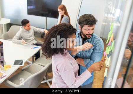 Creative team brainstorming ideas for web design on glass wall in office Stock Photo