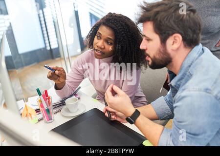 African woman as web designer in the office in collaboration with graphic designer Stock Photo