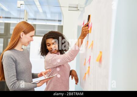 Two young business women in the brainstorming workshop of a design agency Stock Photo