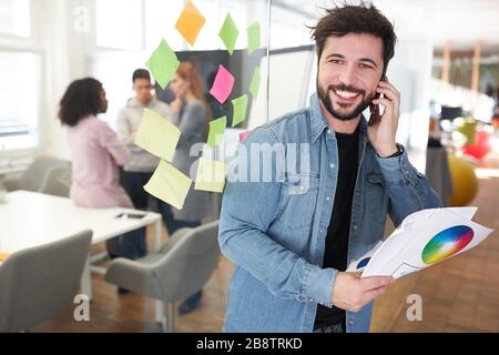 Graphic designer as an entrepreneur with smartphone in the office of an internet agency Stock Photo