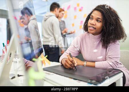 African woman as a graphic designer uses the pen to design a layout on a tablet computer Stock Photo